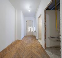 Der Flur in der 3-Zimmer-Wohnung mit einem Boden in Holzoptik und einem Rohr in der Wand.
