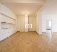 Innenraum einer 3-Zimmer-Wohnung mit weißer Küche und Boden in Holzoptik.
