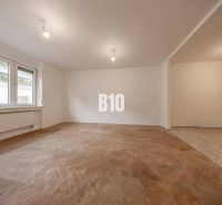 Wohnzimmer in einer 3-Zimmer-Wohnung mit Holzboden und großen Fenstern.