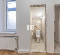 Badezimmer mit Keramikfliesen und Fenster, daneben ein Boden mit Holzdekor.