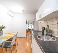 Küche mit Tisch, Stühlen und Boden in Holzoptik in einer 2-Zimmer-Wohnung.