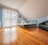 Schlafzimmer im Einfamilienhaus mit Bett, Ledersofa und Holzboden.
