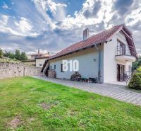 Ein Einfamilienhaus in Marianka, mit Terrasse und Rasen, umgeben von einer Steinmauer.