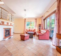 Wohnzimmer in einem Einfamilienhaus mit Kamin, rotem Sofa und Fenstern mit Aussicht.