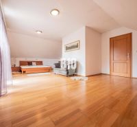 Ein geräumiges, helles Zimmer, Holzboden, Bett und Sessel, Einfamilienhaus.