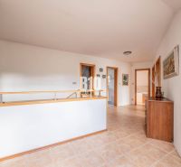 Flur mit Keramikfliesen, Holzgeländer und Schrank in einem Einfamilienhaus.