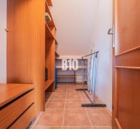 Ein Kleiderschrank in einem Einfamilienhaus mit Schränken, Regalen und Fliesenboden.