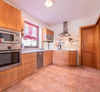Eine Küche in einem Einfamilienhaus mit Fliesenboden, Holzelementen und Edelstahlgeräten.