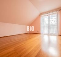 Ein geräumiges Zimmer mit Holzboden und einem französischen Fenster in einem Einfamilienhaus.