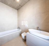 Badezimmer mit gefliester Badewanne in einem Einfamilienhaus. Decke aus Beton.