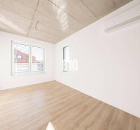 Ein Zimmer in einem Einfamilienhaus mit einem Boden in Holzoptik und großen Fenstern.