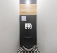 Toilette mit schwarzem Sitz und geometrischem Boden in einer 3-Zimmer-Wohnung.
