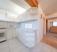 Küche in einem Einfamilienhaus mit weißen Küchenschränken und gefliestem Boden.