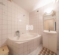 Ein Badezimmer mit Badewanne und Waschbecken in einem Einfamilienhaus, gefliest mit hellen Fliesen.