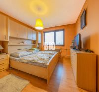 Ein Schlafzimmer in einem Einfamilienhaus mit orangefarbenen Wänden und einem Boden in Holzoptik.