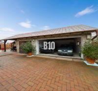 Ein Einfamilienhaus in Štvrtok na Ostrove mit einer Garage für zwei Autos und einem gepflasterten Hof.