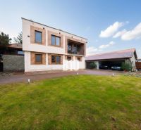 Ein Einfamilienhaus in Štvrtok na Ostrove mit Garage, Rasenfläche und Ziegelfassadendekor.