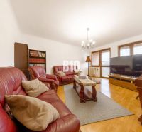 Wohnzimmer in einem Einfamilienhaus mit Ledersofa, Bücherregal und Holzboden.