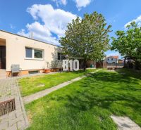 Exterieur eines Einfamilienhauses in Kalinkovo mit Rasen, Bäumen und Terrasse.