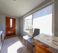 Küche in einem Einfamilienhaus mit sonnigen Fenstern und einem Holztisch.