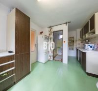 Küche in einem Einfamilienhaus mit grünem Boden und Holzdekor auf den Schränken.