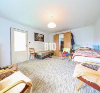 Ein Zimmer mit Bett, Schränken und Sessel in einem Einfamilienhaus. Ein Teppich bedeckt den Boden.