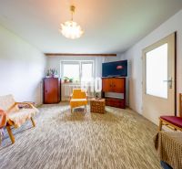 Wohnzimmer in einem Einfamilienhaus mit Teppichboden und einfacher Einrichtung.