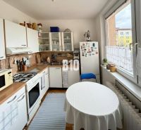 Küche in einer 3-Zimmer-Wohnung mit Tisch, Kühlschrank und Küchenzeile mit Spüle.