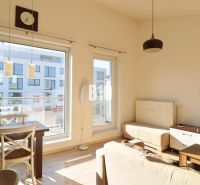 Wohnzimmer in einer 2-Zimmer-Wohnung mit hellen Möbeln und einem Boden in Holzoptik.