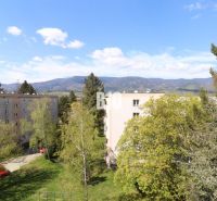 Blick auf Plattenbauten in Martin, umgeben von Grünflächen und Bergen im Hintergrund.