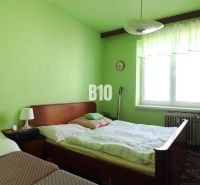 Grünes Schlafzimmer mit zwei Betten und Möbeln in einer 3-Zimmer-Wohnung.