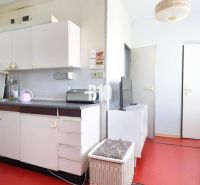 Küche in einer 3-Zimmer-Wohnung mit weißen Möbeln und rotem Boden.