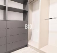Ein Kleiderschrank mit grauen Schränken und einer Kleiderstange in einer Zweizimmerwohnung.