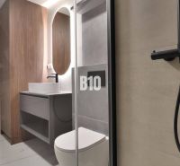 Badezimmer in einer 2-Zimmer-Wohnung mit Holzboden und Duschkabine.