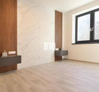 Dieses Zimmer in der 2-Zimmer-Wohnung hat einen Boden mit Holzdekor und eine Wand mit Marmoroptik.