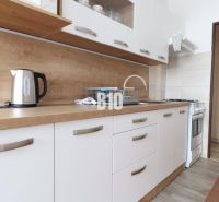 Helle Küche mit weißen Schränken und Arbeitsplatte mit Holzdekor in einer 3-Zimmer-Wohnung.
