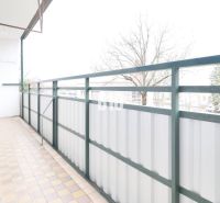 Balkon einer 3-Zimmer-Wohnung mit Blick auf Bäume und Fliesen.