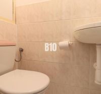 Toilette und Waschbecken im Badezimmer in einer 3-Zimmer-Wohnung mit Fliesen.