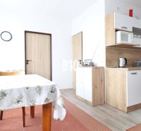 Die Küche in einer 3-Zimmer-Wohnung mit einem Boden in Holzoptik, einem Esstisch und Schränken.