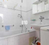 Badezimmer in einer 3-Zimmer-Wohnung mit Badewanne, Waschbecken, Spiegel und Waschmaschine.