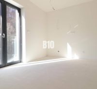 Ein leeres Zimmer in einer 3-Zimmer-Wohnung mit großen Fenstern und Blick auf die Natur.