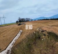 Hügelige Landschaft in Laskári, geeignet für Wohnbaugrundstücke, mit Stromleitungen im Hintergrund.