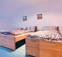 Schlafzimmer mit drei Betten in einer 3-Zimmer-Wohnung. Holzdekorationen, grüner Teppich.