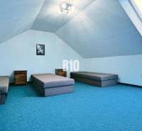 Dachzimmer in einer 3-Zimmer-Wohnung, Sitzgelegenheit und Dachfenster, blauer Teppich.