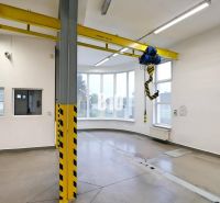 Ein Raum mit einem Kran in einer Produktionshalle mit Betonboden und großen Fenstern.