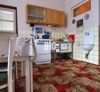Eine Küche in einem Einfamilienhaus mit einem Kachelherd und einem rotbraunen Teppich.