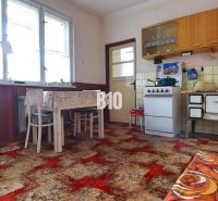 Eine Küche in einem Einfamilienhaus mit Retro-Möbeln, Kacheln und einem auffälligen Teppich.