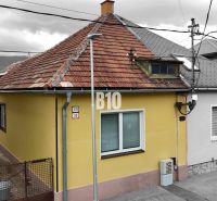 Ein Einfamilienhaus in Martin mit gelber Fassade und schrägem Dach, neben dem Zugangsweg.