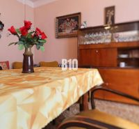 Esszimmer in einem Einfamilienhaus mit Blumen auf dem Tisch, Retro-Möbeln und Gläsern im Schrank.