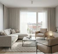 Wohnzimmer mit Sofa, Sesseln und Holzboden in einer Zweizimmerwohnung.